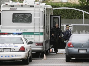 Royal Canadian Mounted Police investigators leave the command center at an apartment tower, the scene of a multiple homicide, in Surrey, British Columbia, October 20, 2007. (REUTERS/Lyle Stafford, file photo)