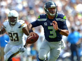 Seattle Seahawks quarterback Russell Wilson looks to pass as San Diego Chargers outside linebacker Dwight Freeney gives chase at Qualcomm Stadium on September 14, 2014. (Jake Roth/USA TODAY Sports)