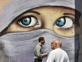 People walk past a mural of a Muslim woman painted on a wall in an inner city suburb in Sydney on October 2, 2014. Australian military jets are to join in the U.S.-led air war against the Islamic State group in Iraq, conducting refuelling and support missions, Prime Minister Tony Abbott said. (AFP PHOTO/Peter PARKS)