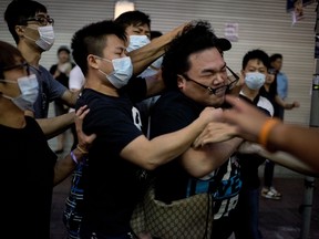 A group of men in masks beat up a man (R) who tried to stop them from removing barricades from a pro-democracy protest area in the Causeway Bay district of Hong Kong on October 3, 2014. (AFP PHOTO / ALEX OGLE)