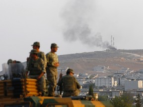 Turkish soldiers are seen on top of an armoured vehicle, with the Syrian town of Kobani in the background, near the Mursitpinar border crossing on the Turkish-Syrian border, in the southeastern Turkish town of Suruc in Sanliurfa province Oct. 3, 2014.REUTERS/Murad Sezer