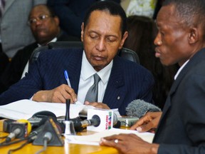 Former Haitian dictator Jean-Claude "Baby Doc" Duvalier signs an affidavit stating that he will appear in court next week, as he attends an appeals court hearing in Port-au-Prince in this February 28, 2013, file photo.  REUTERS/Swoan Parker