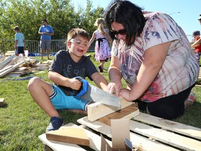 JOHN LAPPA/THE SUDBURY STAR/QMI AGENCYLeane Koskela looks on as her son Kai, 5, tries his hand at sawing at the Learning Spark play-based learning festival at Bell Park in Sudbury, ON. on Saturday, Sept. 27, 2014. The festival, which is hosted by the Greater Sudbury Learning City Initiative, is held to show how children can learn through free unstructured play.