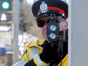 EPS Cst. Jeff Sliwa stands behind a light standard as he takes part in speed enforcement along Scona Road at 94 Avenue, in Edmonton, Alta., on Thursday March 13, 2014. David Bloom/Edmonton Sun/QMI Agency