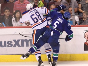 Edmonton Oilers' Tyler Pitlick #68 and Vancouver Canucks’ Luca Sbisa #5 collide during the third period of a pre-season NHL game at Rogers Arena in Vancouver, B.C. on Saturday October 4, 2014. Carmine Marinelli/QMI Agency