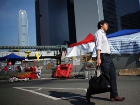 A man walks to work along an area blocked by protesters outside of the government headquarters building in Hong Kong October 6, 2014. REUTERS/Carlos Barria