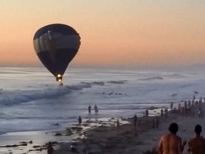 A hot air balloon carrying a man who had just proposed to his girlfriend drifted into the ocean off the Southern California coast, where daring surfers grabbed a rope to pull the aircraft to shore.
(Screenshot from YouTube)