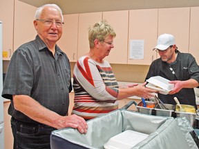 Ken Rolph (left), and Fran Lannin are two volunteers with the Mitchell and Area Community Outreach. They regularly help out with the Meals On Wheels program. Lannin is seen here packing a meal from Ritz Lutheran Villa chef, Shawn Hackett (right). KRISTINE JEAN/SUN MEDIA