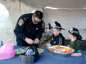 Drayton Valley/Brazeau County Fire Services Lieutenant Kent Fuson unwraps a fire prevention wristband to show Oilton and Dixon Chambers during the fire prevention kick off community event on Oct. 4. See more pictures on pg. 2 and more about Fire Prevention Month on pg. 25.