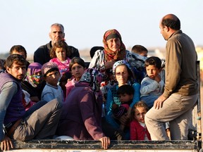 Newly arrived Syrian Kurdish refugees stand at the back of a truck after crossing into Turkey from the Syrian border town Kobani, near the southeastern Turkish town of Suruc in Sanliurfa province October 6, 2014. REUTERS/Umit Bektas