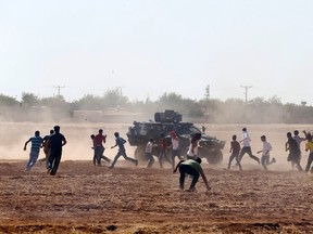 Protesters throw stones at an armoured army vehicle during a pro-Kurdish demonstration in solidarity with people of Kobani, near the Mursitpinar border crossing on the Turkish-Syrian border, in the Turkish town of Suruc in southeastern Sanliurfa province October 7, 2014. Islamic State fighters advanced into the south west of the Syrian Kurdish town of Kobani overnight, a monitoring group said on Tuesday, taking several buildings to gain attacking positions from two sides of the city. (REUTERS/Umit Bektas)