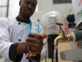 A man washes his hands at a facility outside the Green Pharmacy, Area 8, in Abuja, September 1, 2014. (REUTERS/Afolabi Sotunde)