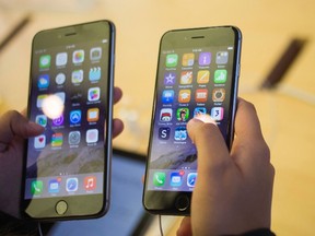 A customer holds an iPhone 6 (R) and iPhone 6 Plus at the Apple store on Fifth Avenue after the phones went on sale in New York in this file photo taken Sept. 19, 2014.  REUTERS/Adrees Latif/Files