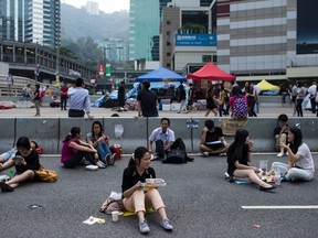 A woman takes her lunch while sitting on a highway, part of an area blocked off by protesters of the Occupy Central movement, in Hong Kong October 7, 2014.     REUTERS/Tyrone Siu