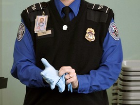 A TSA agent dons rubber gloves at a security checkpoint at Washington Reagan National Airport in Washington, November 22, 2010.REUTERS/Jason Reed