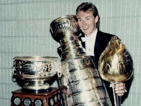 Oilers Wayne Gretzky holds the Stanley Cup along with Hart Memorial Trophy (right) and the Art Ross Trophy during the 1984 NHL Awards in Toronto on May 19, 1984. Gretzky scored 50 goals in 42 games that season. (EDMONTON SUN FILE)