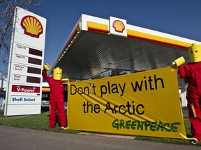 Greenpeace activists hang a banner in front of a Shell gas station in Santiago, Chile, on July 24, 2014. The protest is against Shell's oil search in the Arctic region, and also to demand that Lego remove Shell logos from their toys. (AFP PHOTO/MARTIN BERNETTI)