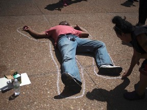 An activist, demanding justice for the shooting death of teen Michael Brown, outlines a man lying on the pavement in front of City Hall in downtown St. Louis, Missouri, August 26, 2014. (REUTERS/Adrees Latif)