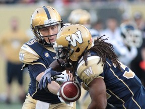 Drew Willy #5 of the Winnipeg Blue Bombers hands off to Paris Cotton #34 in first half action in a CFL pre-season game against the Toronto Argonauts at the Investors Group Field on June 9, 2014 in Winnipeg, Manitoba, Canada.