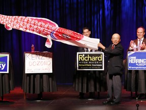 Belleville's mayoral candidate Kenzo Dozono, second from right, is helped by candidate Bill Glisky, left, as he uses a fish kite to share his views on how drawing new residents and visitors to The Friendly city during a Belleville and District Chamber of Commerce debate at The Empire Theatre in downtown Belleville, Ont. Thursday evening, Oct. 9, 2014.  - JEROME LESSARD/THE INTELLIGENCER/QMI AGENCY