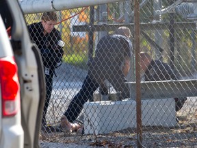 A forensics officer works with colleagues to photograph a body discovered inside Hydro One's Highbury Transmission Station in London, Ont., on October 10, 2014. (CRAIG GLOVER/QMI Agency)