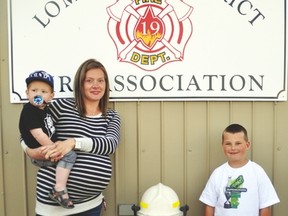 While holding one-year-old son Ryder, Leah Cazemier stands last Thursday next to a fire hydrant that’s in memory of her late husband Bucky Ruggles. On the right is the couple’s son Finn, 6, who Leah was pregnant with when Ruggles died. The fire hydrant is located in front of the Lomond fire hall.  Stephen Tipper Vulcan Advocate