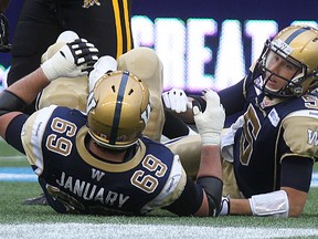 Winnipeg Blue Bombers QB Drew Willy (right) looks at OL Glenn January after being sacked by DE Ted Laurent of the Hamilton Tiger-Cats during CFL action at Investor Group Field in Winnipeg, Man., on Sat., Sept. 27, 2014.