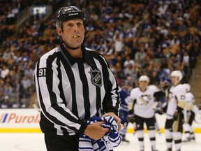 Linesman Don Henderson removes a Maple Leafs jersey that was thrown onto the ice during the Pittsburgh Penguins' 5-2 win in Toronto on Saturday night. (JACK BOLAND/TORONTO SUN).