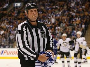 Linesman Don Henderson removes a Leafs jersey that was thrown on the ice in disgust during the Leafs vs. Penguins tilt in Toronto on Saturday, Oct. 11, 2014. (JACK BOLAND/Toronto Sun)