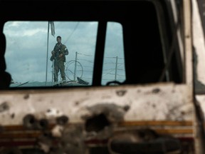 An Afghan policeman is seen through a damaged vehicle, which was hit in a suicide attack in Kabul October 13, 2014. A suicide car bomber rammed a foreign convoy along a major road out of Afghanistan's capital Kabul early on Monday, killing at least one person, authorities said. (REUTERS/Omar Sobhani)