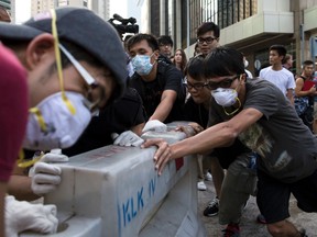 Occupy Central protesters carry a safety barrier filled with water to block a road, after anti-Occupy Central protesters had cleared road blocks, at the main protest site in Admiralty in Hong Kong October 13, 2014. Hundreds of people, some wearing surgical masks and armed with crowbars and cutting tools, tore down protest barriers in the heart of Hong Kong's business district on Monday, scuffling with protesters who have occupied the streets for two weeks.(REUTERS/Tyrone Siu)