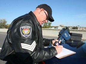 Sgt. Marc Gatien writes down the particulars of one of the vehicles he caught speeding, from his vantage point on the Blair Rd. Transitway overpass on Hwy. 174. Gatien and seven responding officers handed out nearly 30 tickets in just over an hour Monday morning. (DOUG HEMPSTEAD/Ottawa Sun)