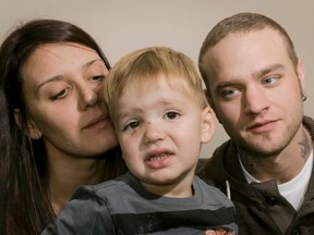 Erin Schaffer and Dallas Wilson mug for a photo with their injured son Jaxon Schaffer-Wilson, almost age 3, inside their home in Calgary, Alta., on Sunday, Oct. 12, 2014. Jaxon was attacked in the face by a Shih Tzu, and his dad says the owner left without giving him any contact information. Lyle Aspinall/Calgary Sun/QMI Agency