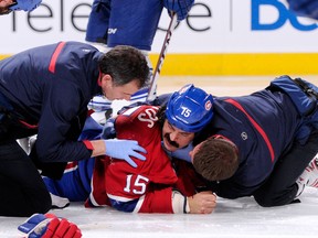 George Parros #15 of the Montreal Canadiens is tended to by Canadiens staff after falling head first on the ice during a fight in the NHL game against the Toronto Maple Leafs at the Bell Centre on October 1, 2013 in Montreal, Quebec, Canada. (Richard Wolowicz/Getty Images/AFP)