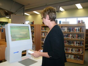 Drayton Valley Municipal Library Director Sandy Faunt demonstrates how to check out a book with the new self-check system at the main branch of the Drayton Valley Municipal Library located at the Drayton Valley Civic Centre.