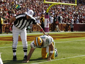 Green Bay Packers quarterback Aaron Rodgers is assisted by an unidentified NFL official after being tackled by the Washington Redskins defence during their NFL football game on October 10, 2010. Rodgers suffered a head concussion on his last pass of the game. (REUTERS/Larry Downing)