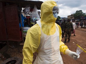 A health worker in protective equipment holds on to equipment used to take swabs for laboratory testing near Rokupa Hospital, Freetown October 6, 2014. (REUTERS/Christopher Black)