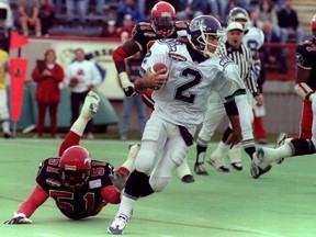 Toronto Argonauts quarterback Doug Flutie eludes the tackle of Calgary Stampeders linebacker Alondra Johnson in the second quarter of their CFL game on October 14, 1996. (QMI Agency)