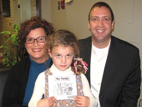 Molly Cordeiro, 6, holds a book she read to the Lambton Kent District School Board of trustees during a meeting Tuesday in Chatham after improving her reading skills through the Summer Literacy Learning Program. Molly is pictured with her mother Jennifer Cordeiro and Eryn Smit, vice-principal of Queen Elizabeth II Public School, who runs the program in Chatham. (ELLWOOD SHREVE  ellwood.shreve@sunmedia.ca)