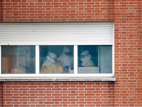 Health workers in protective suits work in a room at an isolation ward on the sixth floor at Madrid's Carlos III Hospital October 15, 2014. REUTERS/Susana Vera