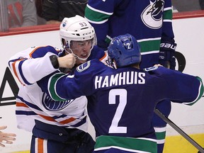 Edmonton Oilers' Ryan Nugent-Hopkins #93 (left) and Vancouver Canucks’ Dan Hamhuis #2 (right) fight during the third period of NHL game at Rogers Arena in Vancouver, B.C. on Saturday October 11, 2014. (Carmine Marinelli/QMI Agency)