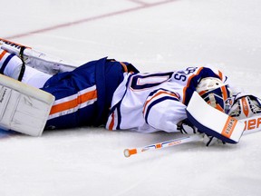 Oct 15, 2014; Glendale, AZ, USA; Edmonton Oilers goalie Ben Scrivens (30) lays on the ice injured as defenseman Andrew Ference (21) looks on during the second period against the Arizona Coyotes at Gila River Arena. Mandatory Credit: Matt Kartozian-USA TODAY Sports