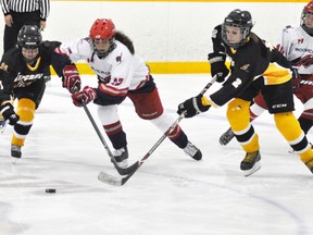 Emily Brintnell (11) and Dani Schoonderwoerd (2) of the Mitchell Midget girls hockey team double-team this Woolwich opponent for the puck during round-robin action from the 9th annual Mitchell Women's Hockey tournament Thursday, Oct. 16. Mitchell rallied from a 1-0 deficit to win, 4-1. ANDY BADER/MITCHELL ADVOCATE