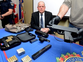 Det. Sgt. Chris McCoy looks over automatic handguns part of a drug seizure. (MORRIS LAMONT, The London Free Press)