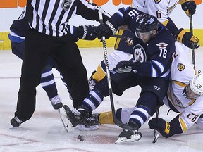 Winnipeg Jets forward Andrew Ladd loses his balance in the faceoff circle against Nashville Predators centre Paul Gaustad during NHL action at MTS Centre, Friday. Kevin King/Winnipeg Sun