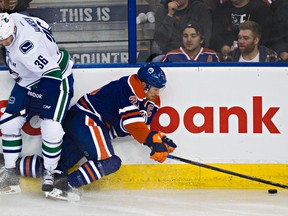 Edmonton's Andrew Ference (21) is hit by Vancouver's Jannik Hansen (36) during the third period of the Edmonton Oilers' NHL hockey game against the Vancouver Canucks at Rexall Place in Edmonton, Alta., on Friday, Oct. 17, 2014. Codie McLachlan/Edmonton Sun/QMI Agency