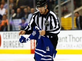 NHL linesman Mike Shewchyk removes a Dion Phaneuf jersey from the ice at the Air Canada Centre in Toronto, Oct. 17, 2014. (JACK BOLAND/QMI Agency)