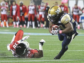 Winnipeg Blue Bombers RB Paris Cotton breaks a tackle from Calgary Stampeders DB Buddy Jackson to score a fourth-quarter touchdown during CFL action at Investors Group Field in Winnipeg, Man., on Sat., Oct. 18, 2014. Kevin King/Winnipeg Sun/QMI Agency