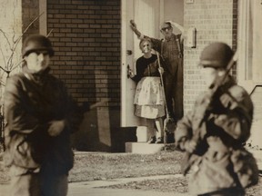 Bewildered Montrealers stare at soldiers patrolling behind their home during the FLQ crisis in 1970.
File photo