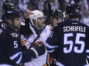 Calgary Flames forward Devin Setoguchi gets tangled up in front of the Winnipeg Jets net with defenceman Mark Stuart and centre Mark Scheifele during NHL action at MTS Centre in Winnipeg, Man., on Sun., Oct. 19, 2014. The Jets visit the Flames on Monday night. (Kevin King/Winnipeg Sun/QMI Agency file)